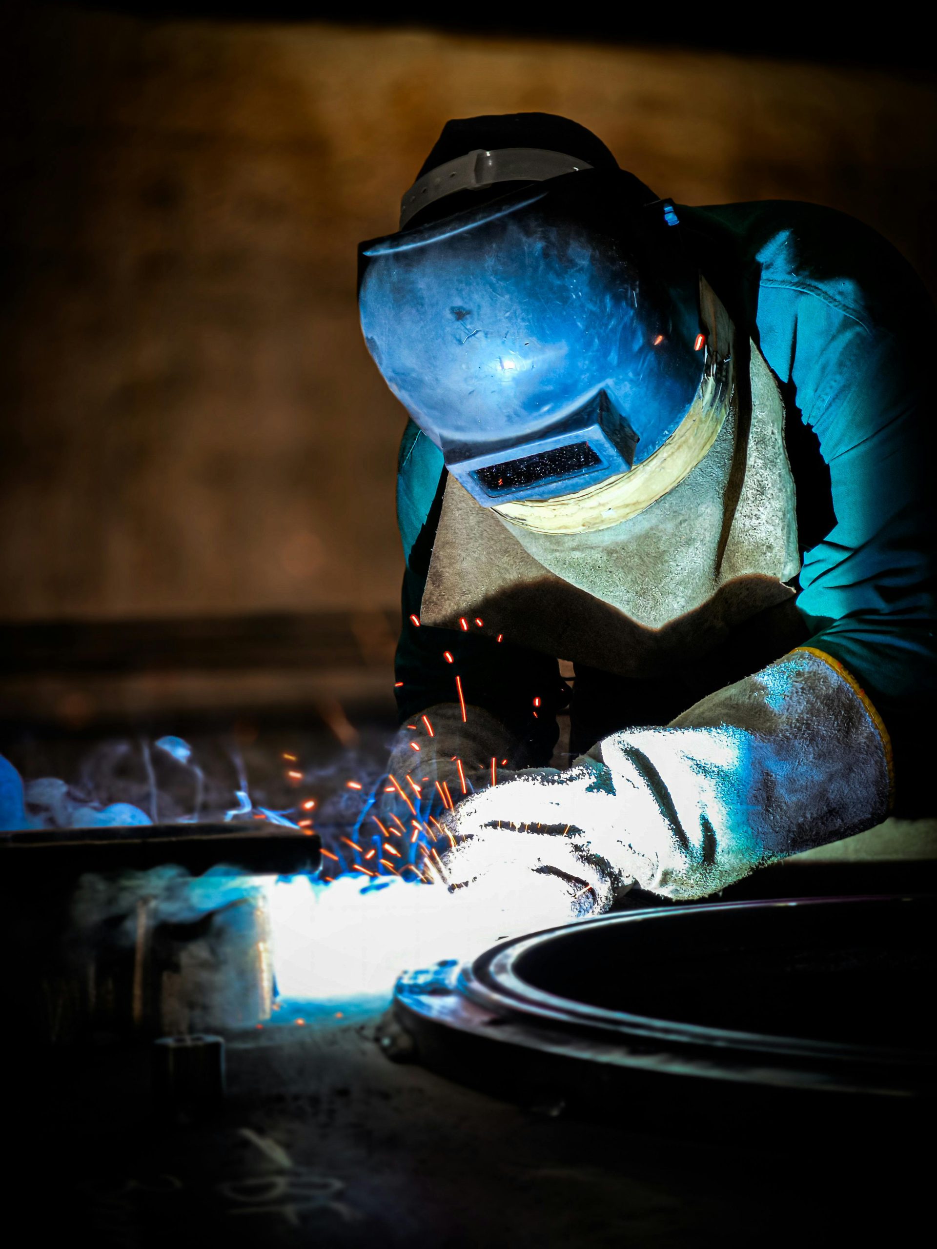Close-up of a welder working with sparks in a dimly lit workshop.